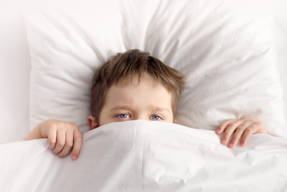 Мальчик зарылся под одеяло в постели