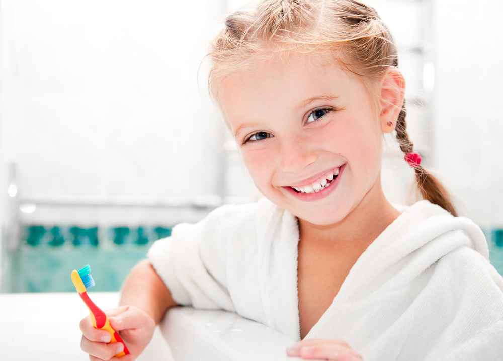 ​Дівчинка в халаті із зубною щіткою