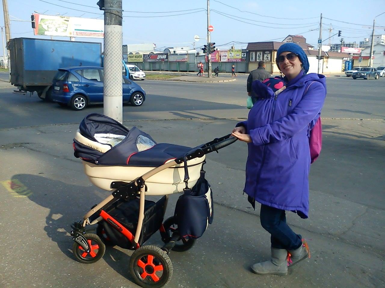 Мама з малюком у слінгу з  коляскою