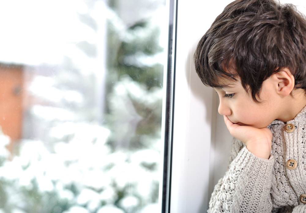 ребенок грустно смотрит в окно