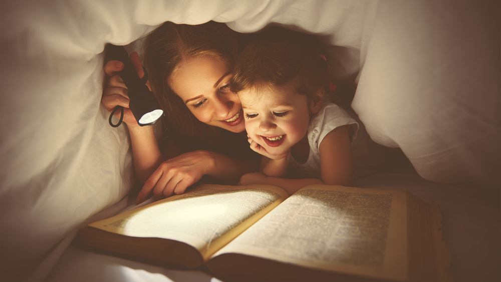 Мама и ребенок читаю и учат стихи под одеялом