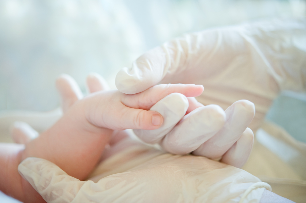 ​Лікар тримає новонародженого за руку