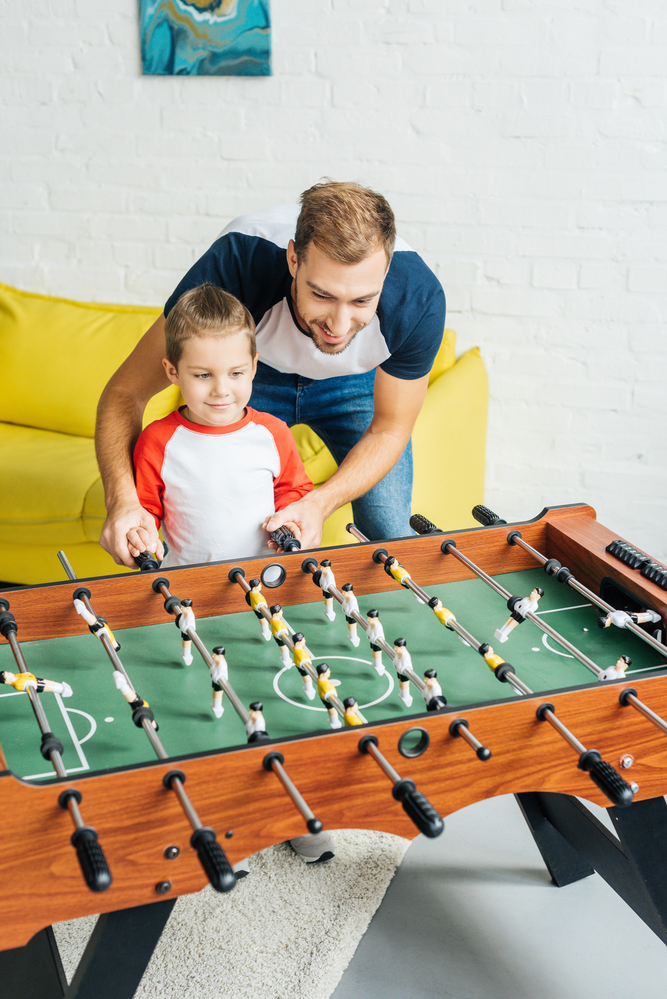 Папа с сыном играют в настольный футбол