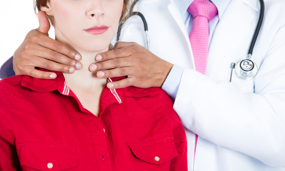 Лікар мацає щитовидну залозу у жінки