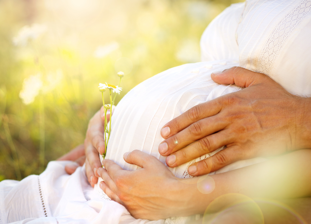Мужские руки обнимают беременный живот женщины