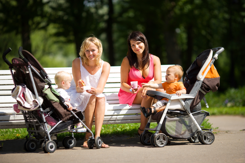 Молодые мамы с колясками на прогулке с детьми в парке