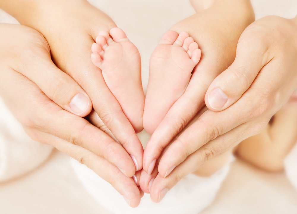 Ножки младенца и родительские руки