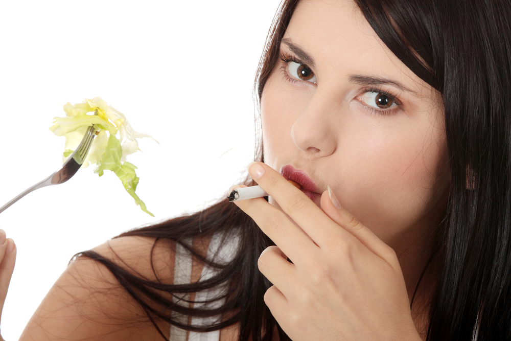 Девушка курит и ест салат