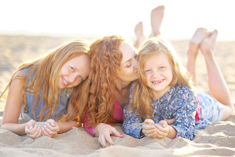Мама і доньки обіймаються на піску
