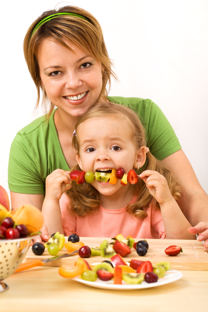Мама і дочка їдять фрукти зі шпажки