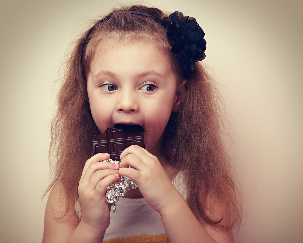 Девочка ест шоколад