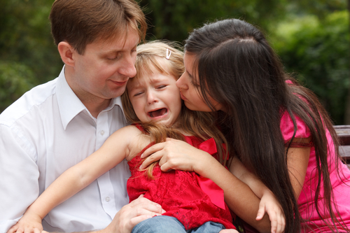 Девочка плачет на руках у родителей