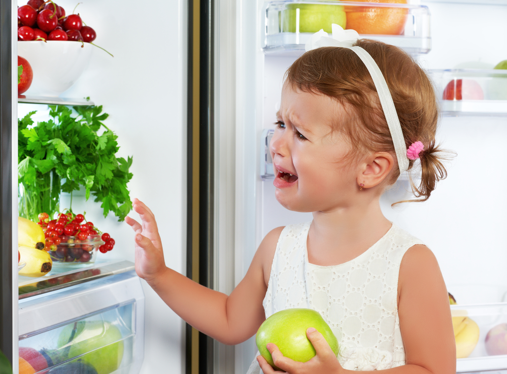 Капризная девочка у холодильника