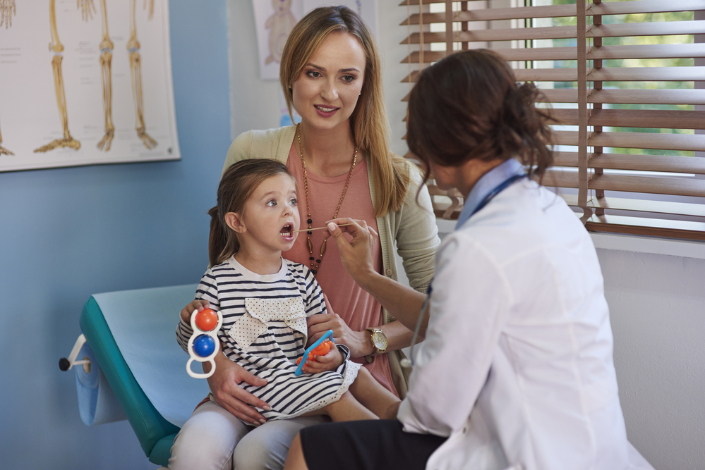 Доктор осматривает горло ребенка