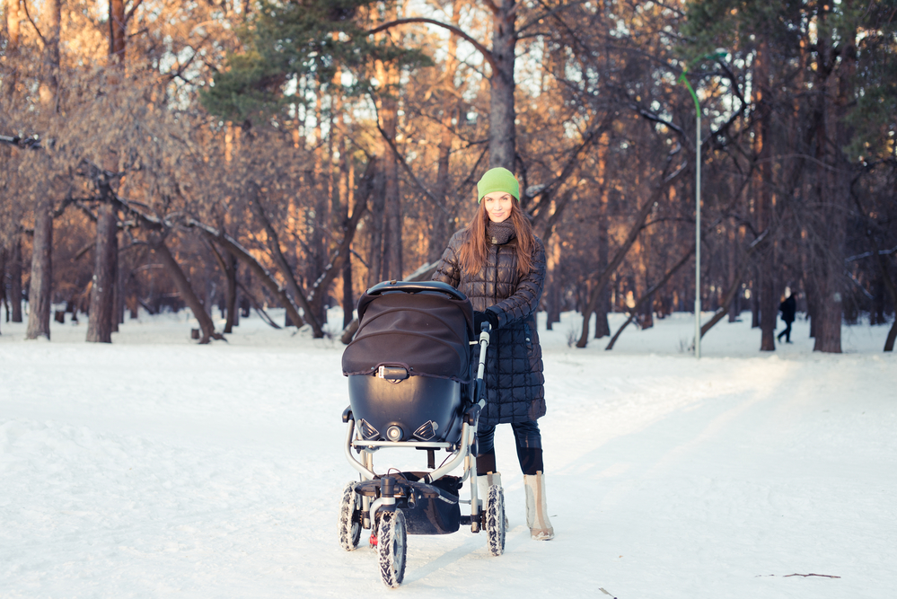 Мама з коляскою на прогулянці взимку