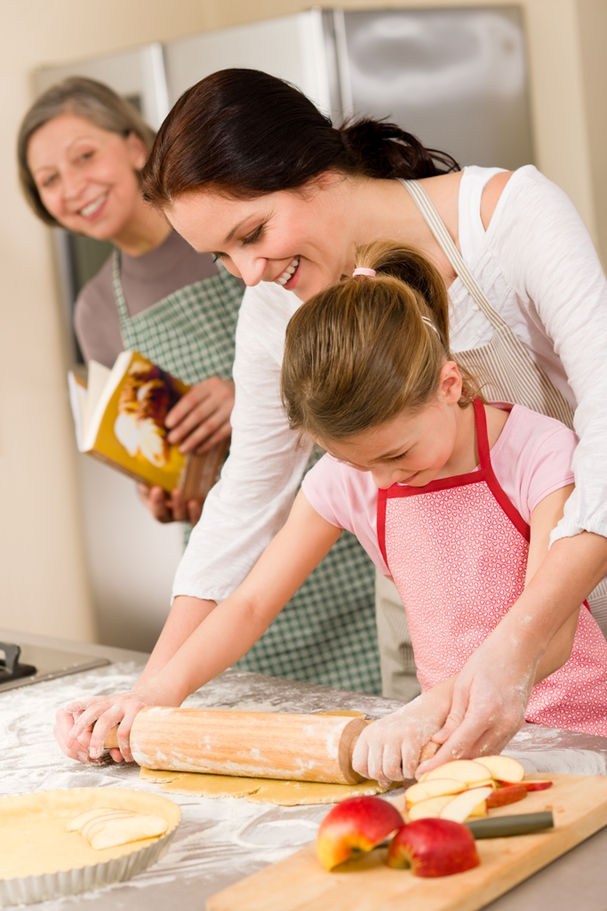 Ребенок с мамой и бабушкой готовит еду на кухне