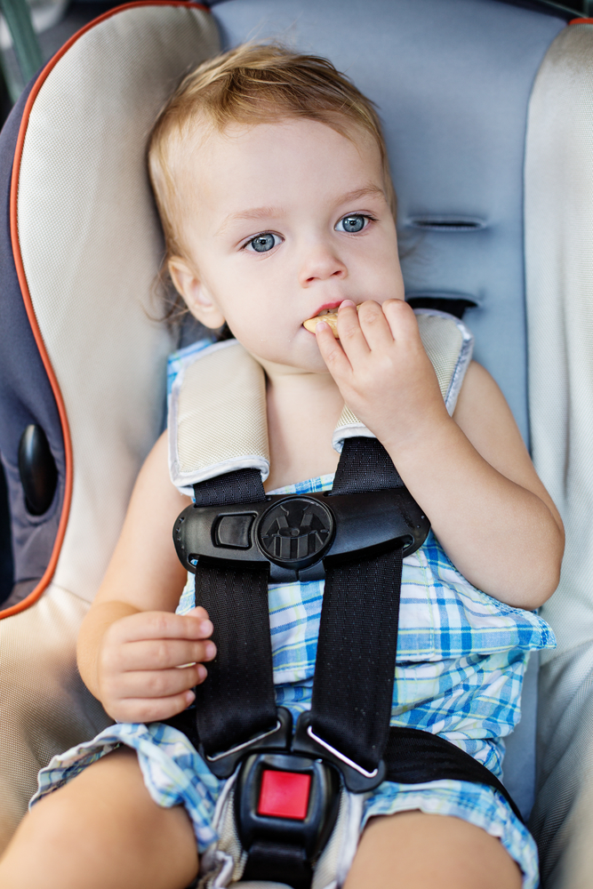 Малыш ест печенье в машине во время путешествия